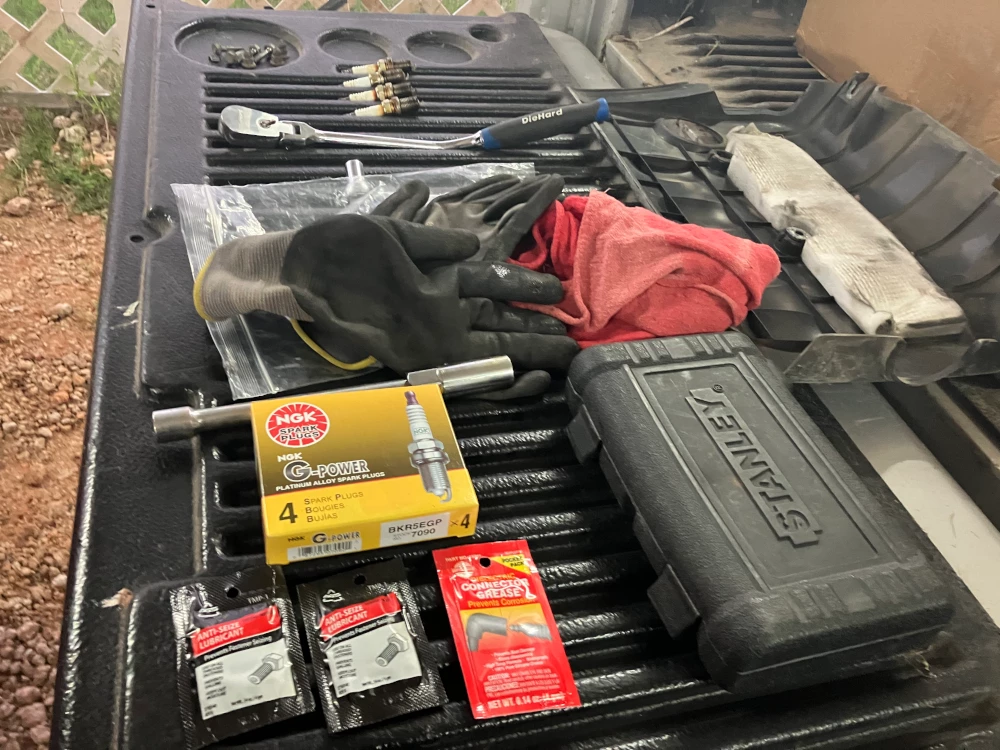 Picture of all the tools I used for this maintenance, gloves, spark plugs, ratchet, ratchet set, anti-seize, dielectric grease.